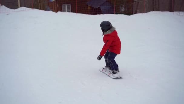 El joven instructor de snowboard aconseja al niño cómo montar una tabla de snowboard. Concepto de actividades invernales. Disparo en cámara lenta — Vídeos de Stock