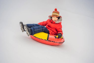 Çocuk kar tüpünde eğleniyor. Çocuk bir boruya biniyor. Çocuklar için kış eğlencesi