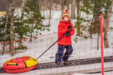 Boruları olan çocuk dağa giden bir travelatörde yükseliyor. Çocuk kar tüpünde eğleniyor. Çocuk bir boruya biniyor. Çocuklar için kış eğlencesi