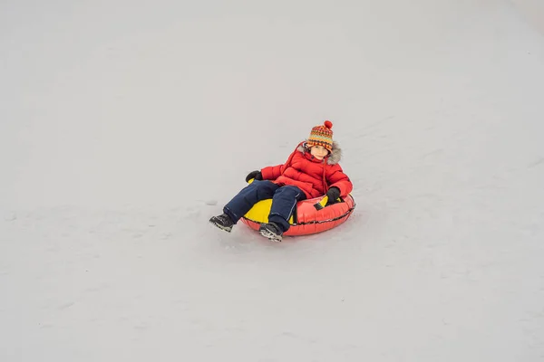 Dziecko bawiące się na snowtubie. Chłopak jedzie na rurze. Zimowa zabawa dla dzieci — Zdjęcie stockowe