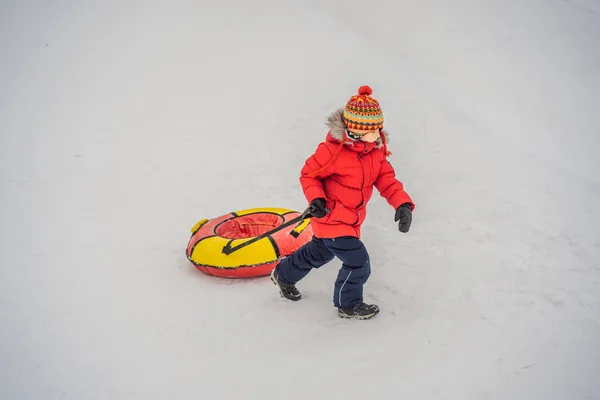 Дитина розважається на сніговій трубці. Хлопчик їде на трубці. Зимові забави для дітей — стокове фото