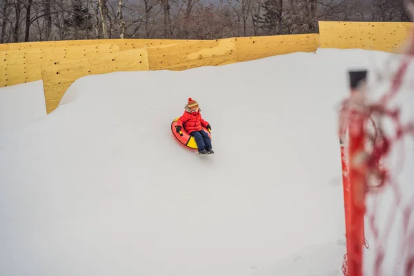 A gyerek jól érzi magát a hócsőben. Csövön lovagol. Téli szórakozás gyerekeknek — Stock Fotó