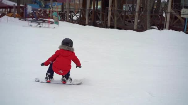 Młody człowiek instruktor snowboardu tiches mały chłopiec jak jeździć na snowboardzie. Koncepcja aktywności zimowej. Strzał zwolniony — Wideo stockowe