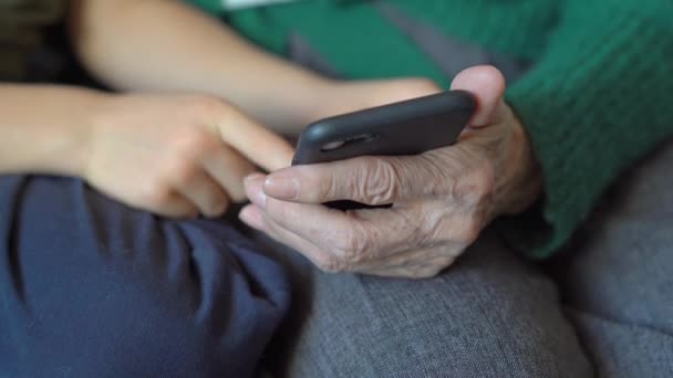 Το αγοράκι δείχνει στη γιαγιά του πώς να χρησιμοποιεί ένα smartphone. Έννοια των νέων τεχνολογιών. — Αρχείο Βίντεο