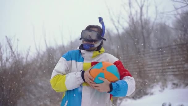 Hombre divertido en una máscara de buceo con una bola inflable se levanta bajo una nevada. Perdido en el tiempo — Vídeos de Stock