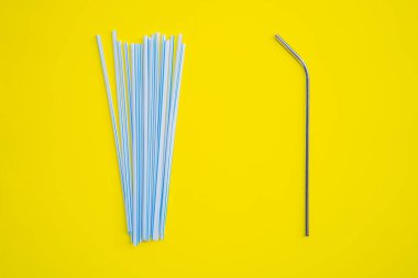 Sarı arka planda çelik içki ve tek kullanımlık pipetler. Sıfır atık