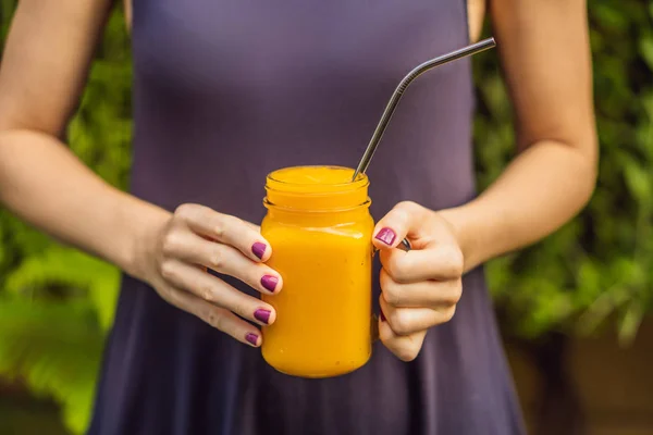 Smoothie à la mangue et paille à boire en acier dans les mains — Photo