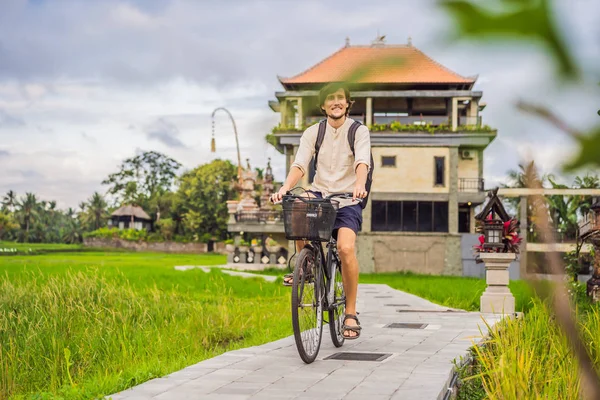 Молодой человек едет на велосипеде по рисовому полю в Убуде, Бали. Путешествие на Бали — стоковое фото