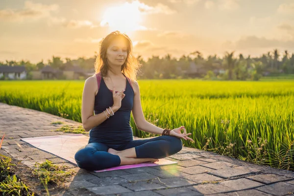 Mujer joven practica yoga al aire libre en campos de arroz por la mañana durante el retiro de bienestar en Bali — Foto de Stock