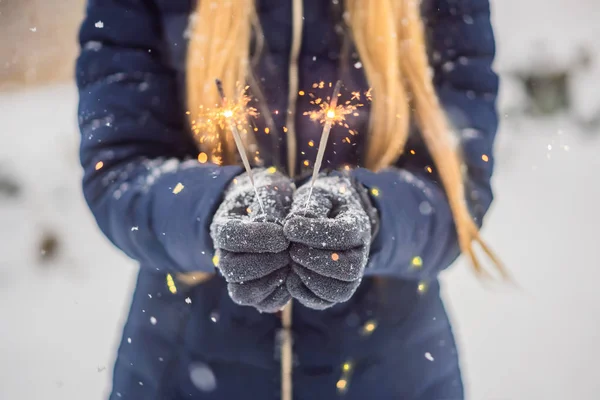 Искры в женских руках на фоне снегопада. Концепция Рождества и Нового года — стоковое фото
