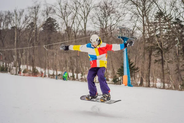 Junger Mann springt mit Snowboard in den Bergen — Stockfoto