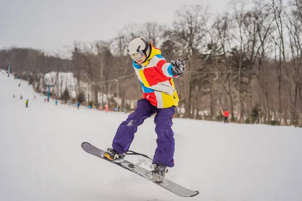 Fiatalember ugrik egy snowboarddal a hegyekben — Stock Fotó