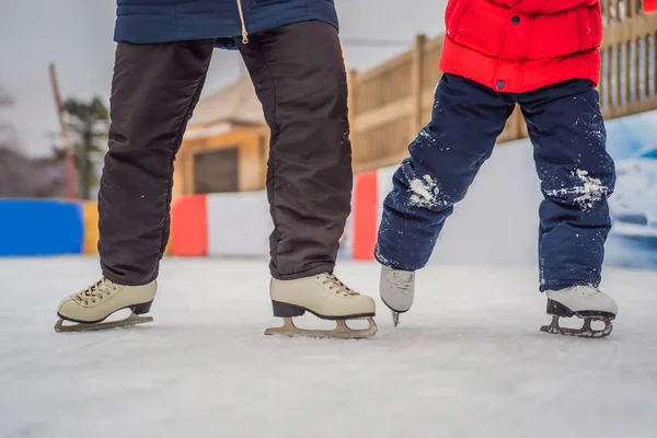 Die junge Mutter bringt ihrem kleinen Sohn das Eislaufen auf der Eisbahn bei. Familie genießt den Winter auf der Eisbahn im Freien — Stockfoto