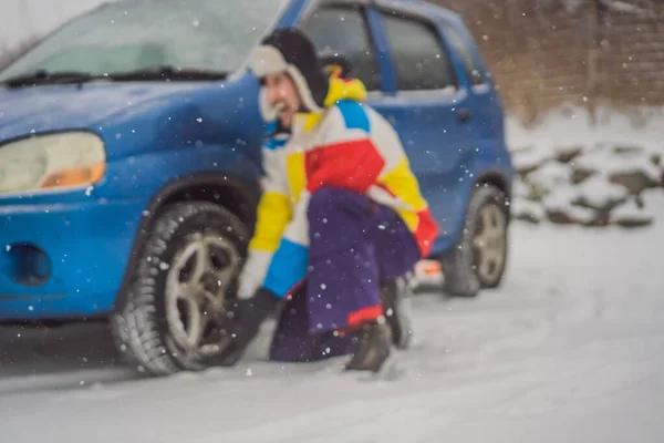 Incidente invernale sulla strada. Un uomo cambia una ruota durante una nevicata. Problemi invernali — Foto Stock