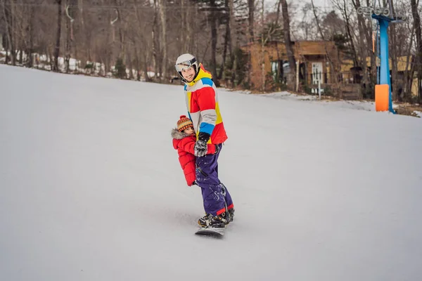 Папа и сын катаются на одном сноуборде, нарушая меры безопасности — стоковое фото