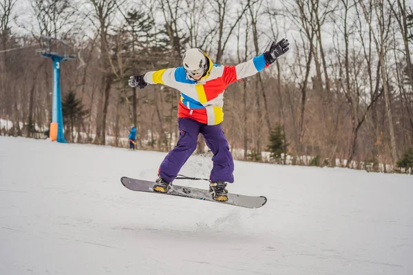 Jovem pulando com um snowboard nas montanhas — Fotografia de Stock