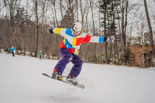 Fiatalember ugrik egy snowboarddal a hegyekben — Stock Fotó