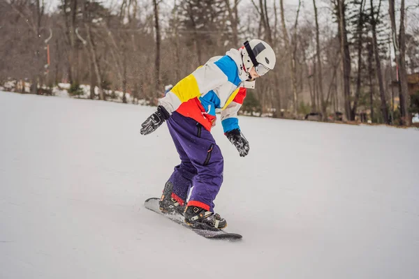 Fiatalember ugrik egy snowboarddal a hegyekben — Stock Fotó