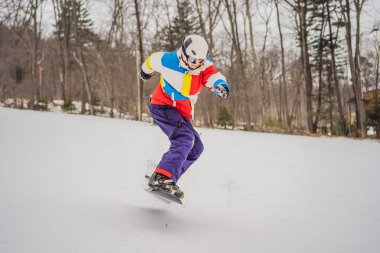 Genç adam dağlarda snowboard 'la atlıyor.