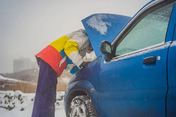 Jóvenes molestos mirando bajo el capó coche roto en la carretera de invierno —  Fotos de Stock