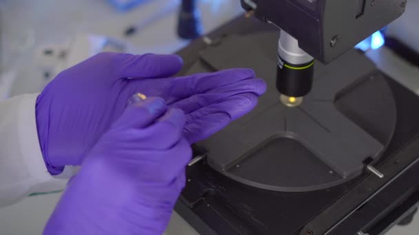 Scientist in a laboratory uses a microscope. He investigates drugs or powders — Stock Video