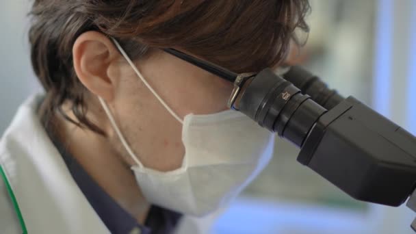 Laboratuvardaki bilim adamları mikroskop kullanır ve notlar alır. Yakın çekim. — Stok video