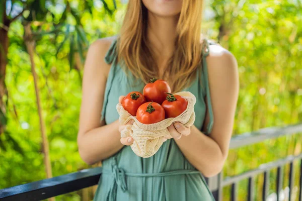 Tomates en una bolsa reutilizable en manos de una joven. Concepto de cero residuos — Foto de Stock