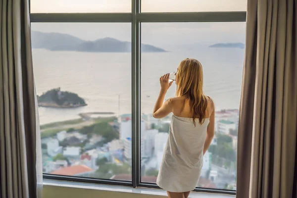 Donna beve acqua al mattino su uno sfondo di una finestra con vista sul mare — Foto Stock