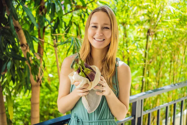 Berinjela em um saco reutilizável nas mãos de uma jovem mulher. Conceito de resíduo zero — Fotografia de Stock