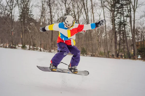Joven saltando con una tabla de snowboard en las montañas —  Fotos de Stock