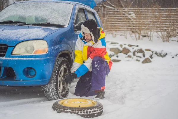 Зимова аварія на дорозі. Чоловік змінює колесо під час снігопаду. Зимові проблеми — стокове фото