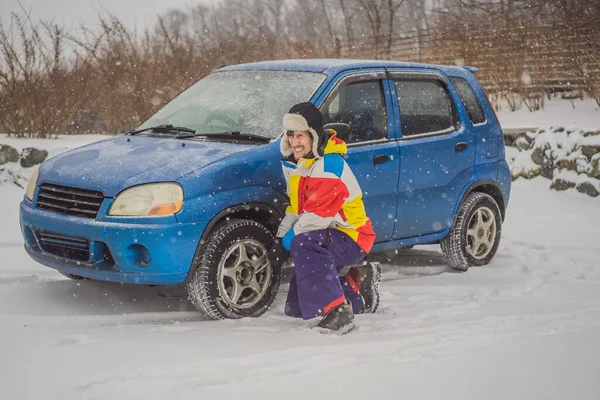 Incidente invernale sulla strada. Un uomo cambia una ruota durante una nevicata. Problemi invernali — Foto Stock