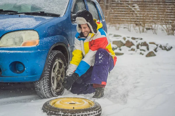 Зимова аварія на дорозі. Чоловік змінює колесо під час снігопаду. Зимові проблеми — стокове фото