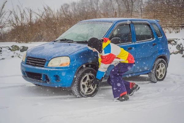Зимняя авария на дороге. Человек меняет колесо во время снегопада. Зимние проблемы — стоковое фото