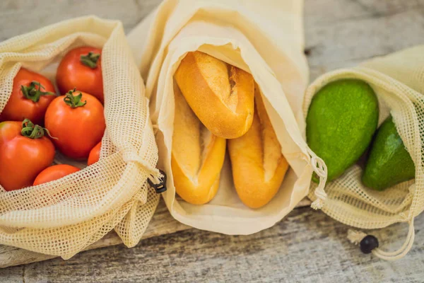 Свежий хлеб, авокадо и помидоры в многоразовой сумке на стильной деревянной кухонной поверхности. Концепция нулевых отходов — стоковое фото