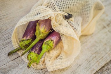 Havalı ahşap mutfak yüzeyinde yeniden kullanılabilir bir çantada patlıcan. Sıfır atık