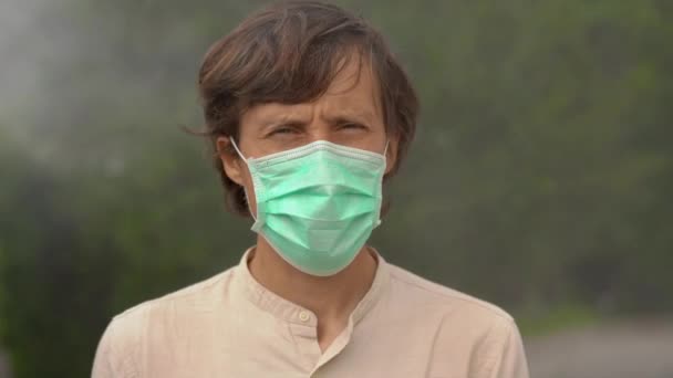 Young man in a medical mask stands in a foggy air. Air pollution concept. Dangerous air concept — Stock Video