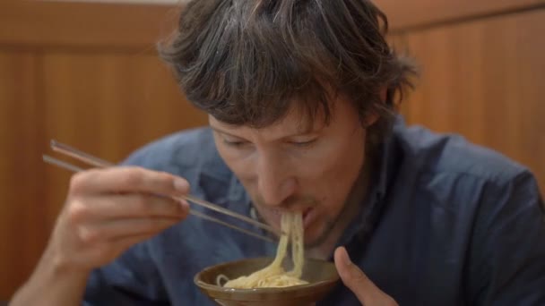 Giovane in un ristorante coreano mangia tradizionale noodle coreano Udon — Video Stock