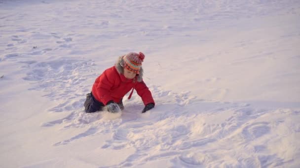 Um rapazinho a brincar na neve com a mãe. Tiro em câmara lenta — Vídeo de Stock