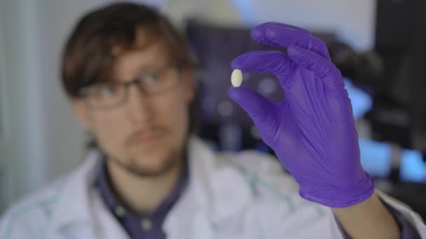 Cientista em um laboratório investiga drogas ou pílulas — Vídeo de Stock