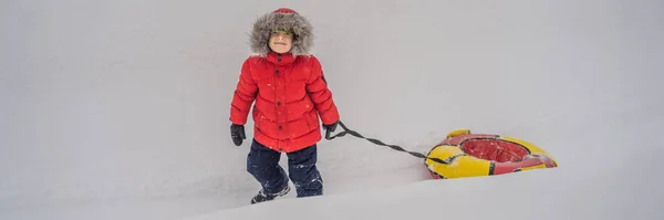 Ребенок веселится на снегоходе. Мальчик ездит на трубе. Зимние развлечения для детей баннер, длинный формат — стоковое фото