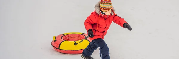 Niño divirtiéndose en tubo de nieve. El chico está montando un tubo. Diversión de invierno para niños BANNER, FORMATO LARGO — Foto de Stock