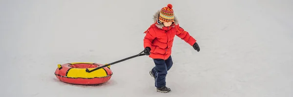 Barnet har kul på snöslangen. Pojken åker slang. Vinternöje för barn Banner, Long Format — Stockfoto