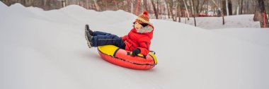 Çocuk kar tüpünde eğleniyor. Çocuk bir boruya biniyor. Çocuklar için kış eğlencesi Banner, Uzun Format