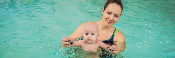 Beautiful mother teaching cute baby girl how to swim in a swimming pool. Child having fun in water with mom BANNER, LONG FORMAT Royalty Free Stock Photos