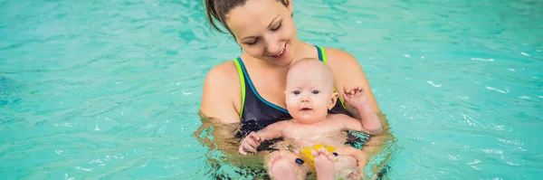 Beautiful mother teaching cute baby girl how to swim in a swimming pool. Child having fun in water with mom BANNER, LONG FORMAT