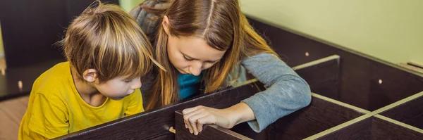 Mother and son assembling furniture. Boy helping his mom at home. Happy Family concept BANNER, LONG FORMAT