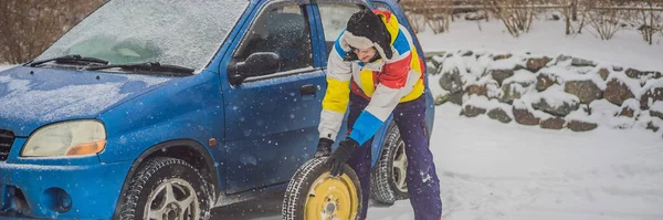 Acidente de inverno na estrada. Um homem muda uma roda durante uma queda de neve. Problemas de inverno BANNER, LONG FORMAT — Fotografia de Stock