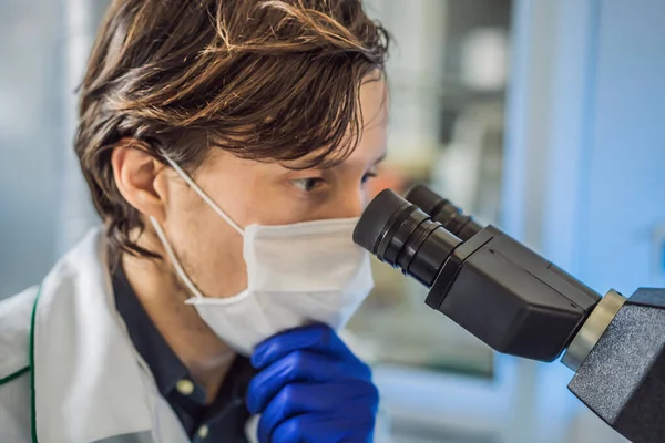 Portrait d'un chimiste mâle caucasien chercheur scientifique utilisant le microscope dans le coronavirus intérieur du laboratoire — Photo