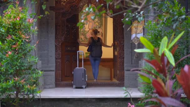 Μια γυναίκα ταξιδιώτης έρχεται στο παραδοσιακό σπίτι του Μπαλί. Ταξίδι στο Μπαλί έννοια — Αρχείο Βίντεο
